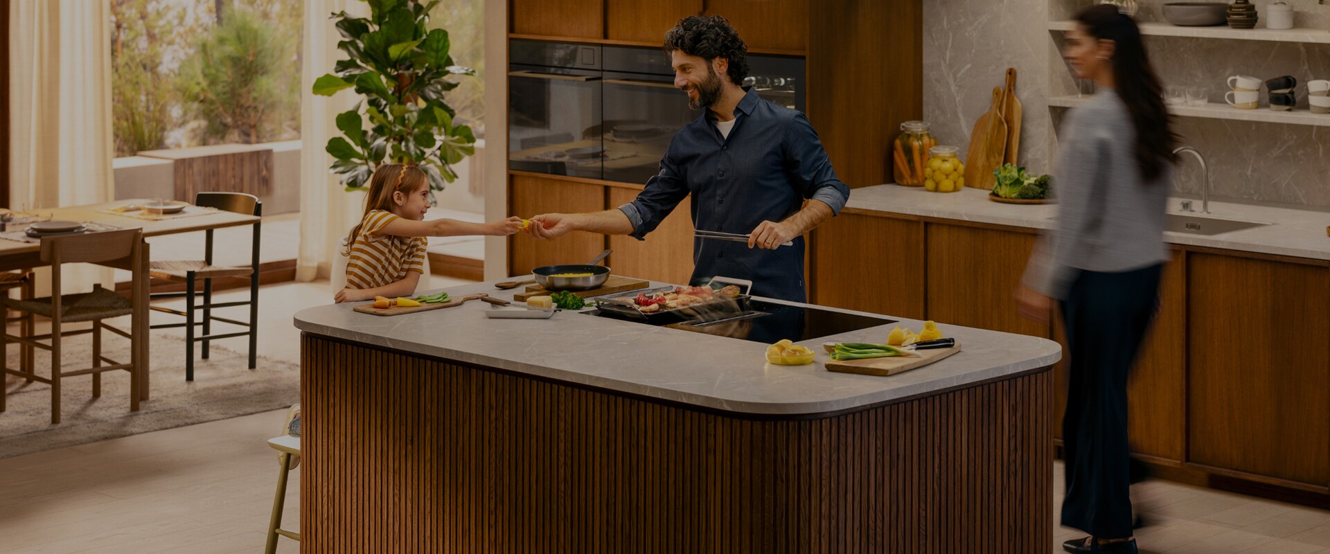 Une famille prépare le dîner ensemble dans une cuisine moderne avec des appareils de cuisine Electrolux