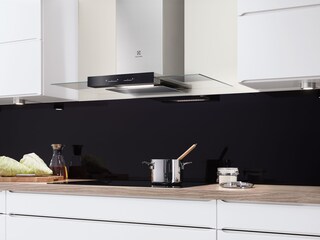 Hotte cheminée en acier inoxydable et verre au-dessus d'une casserole sur une table à induction