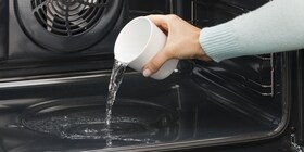 Iemand die water onderin het reservoir van de oven giet