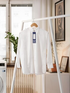 Chemise blanche portant une étiquette de blanchisserie suspendue dans un salon