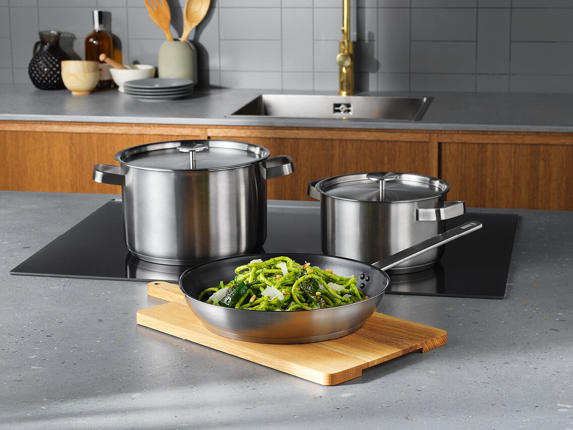 Een Electrolux keuken met een ingebouwde AEG inductiekookplaat met pannen erop en op het aanrecht een snijplank met een keukenpan en voedsel erop.